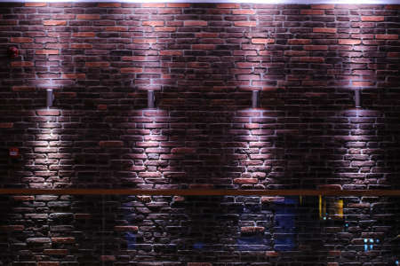Dark room shined brick wall illuminated with ceiling light, vintage style.の写真素材