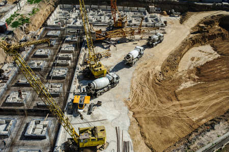 white mixers and yellow crane at the construction site of a building in summer daysの写真素材