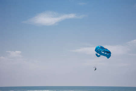 a man with the blue parachute riding on the water at the seasideの写真素材