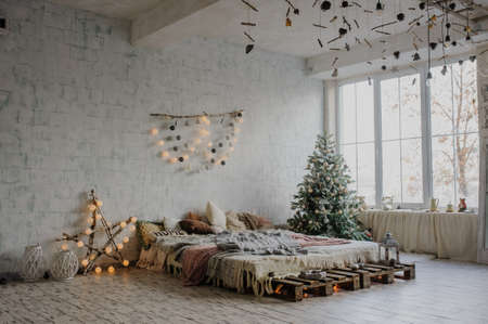White vintage room, decorated for christmas with: pellets bed, tree with presents and toys, Christmas Balls, and big window.の写真素材