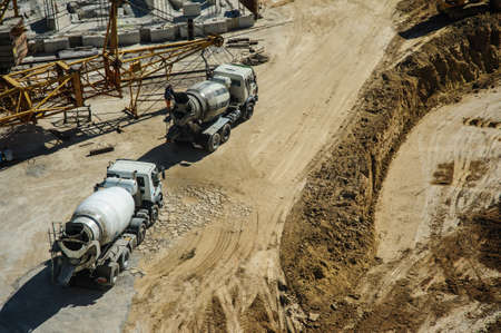 white mixers and yellow crane at the construction site of a building in summer daysの写真素材