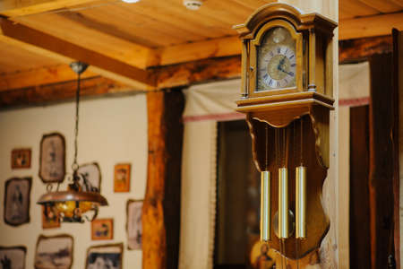 Antiquarian wooden clock with a pendulum in a retro interiorの写真素材