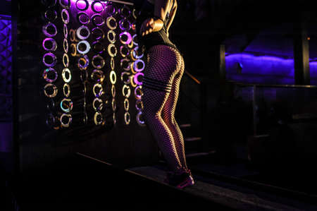 Young sexy dancer dancing on dark background with flashes effect in night clubの写真素材