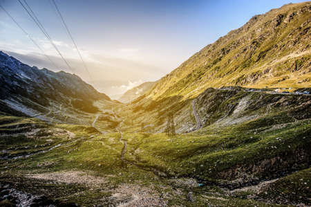 Serpentine curve mountain road shot from high point on sunset. Epic view at the foot of the mountains.の写真素材