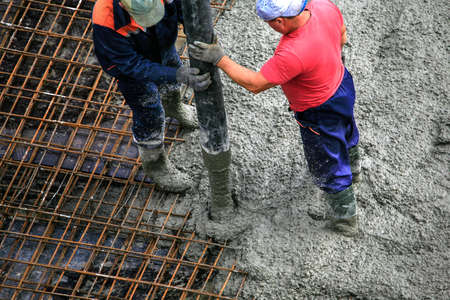 Top view of builders in red shirt works on the construction site: pouring concrete for foundationの写真素材