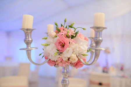 Metallic candlestick from silver decorated with white roses and pink eustoma