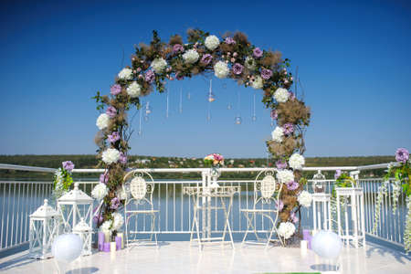 wedding flowers decoration from ranunculus and roses. Beautiful arch for reception on the lakeの写真素材