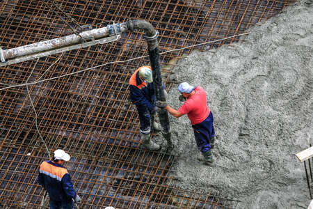 Top view of builders in red shirt works on the construction site: pouring concrete for foundationの写真素材
