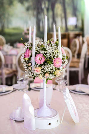 White vintage candlestick decorated with eustoma, roses and gypsophila on the table in a restaurantの写真素材