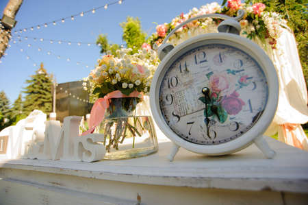 Design elements for wedding: vase of flowers near vintage clock on the white tableの写真素材