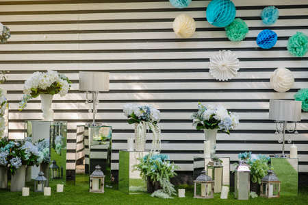 Party wedding decoration outdoor. Vintage metallic style, flowers decoration  from: roses, hortensia and ranunculus. Vase from mirror. Candle on the floorの写真素材
