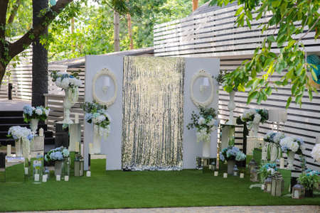 Party wedding decoration outdoor. Vintage metallic style, flowers decoration  from: roses, hortensia and ranunculus. Vase from mirror. Candle on the floorの写真素材