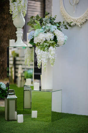 Party wedding decoration outdoor. Vintage metallic style, flowers decoration  from: roses, hortensia and ranunculus. Vase from mirror. Candle on the floorの写真素材