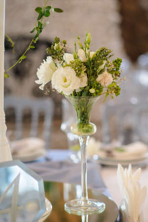 Composition from white eustomas in transparent glasses vase on the table. Wedding decorationの写真素材