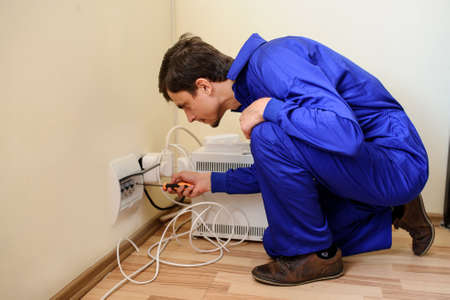 Young handsome electrician man is repair the electrical installationの写真素材