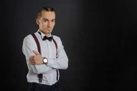 Young handsome boy in white shirt with bowtie, clock on hand, clouse view
with black backgroundの写真素材
