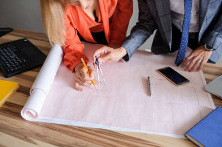 A office desk with architecture project and working handsの写真素材