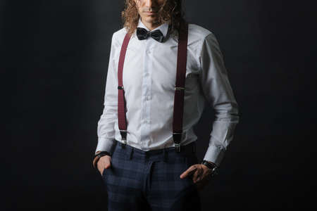 Young handsome boy in white shirt with tie and glases, hands in pockets, with black backgroundの写真素材