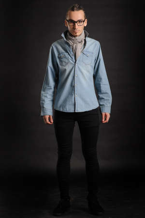 Young handsome boy in denim shirt and glases, curly hair, 
with black backgroundの写真素材