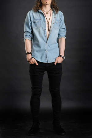 Young handsome boy in denim shirt and glases, curly hair, hands in pockets,
with black backgroundの写真素材