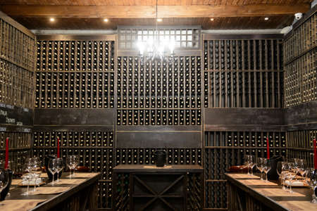 The wine room with a lot of buttles, wooden shelves and red candlesの写真素材