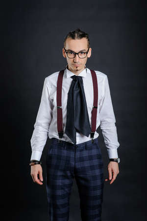 Young handsome boy in white shirt with tie and glases with black backgroundの写真素材