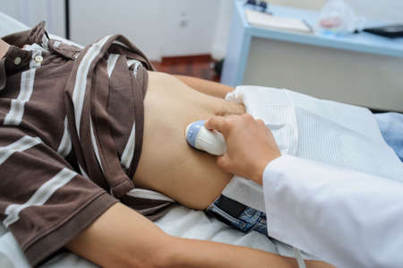 The lady  doctor  examination a man at abdomen with ultrasonography deviceの写真素材
