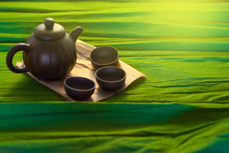 Three cups and a kettle of ceramics on the green background, close viewの写真素材