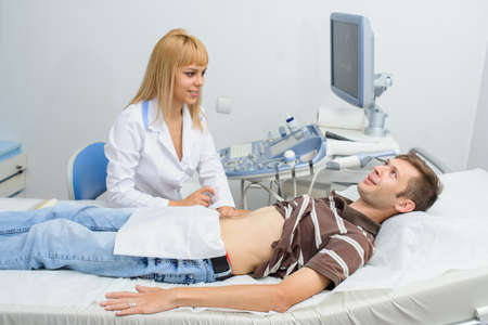 The lady  doctor  examination a man at abdomen with ultrasonography deviceの写真素材