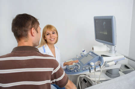 The lady ultrasunography doctor is explaining to the patientat divice, in medical officeの写真素材