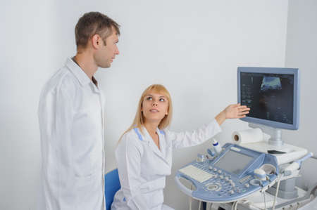 Two doctors looking at the ultrasonography divice in a medical officeの写真素材