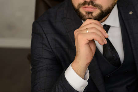 The handsome, caucasian man in a grey suit with a tie, clouse view at his handの写真素材