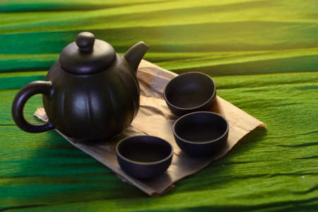 Three cups and a kettle of ceramics on the green background, close viewの写真素材