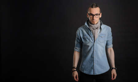 Young handsome boy in denim shirt and glases, curly hair, 
with black backgroundの写真素材