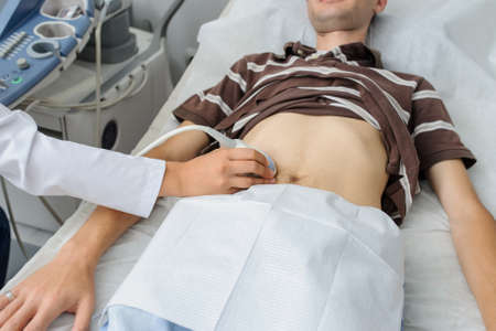 The lady  doctor  examination a man at abdomen with ultrasonography deviceの写真素材
