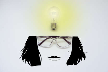 Glasses and a light bulb with a cartoon face, top view, white backgroundの写真素材