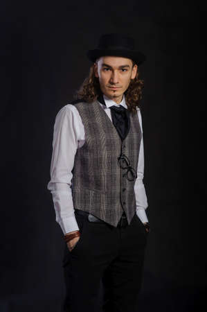 The handsome caucasian young man in a white shirt, suit and hat standing, black backgroundの写真素材