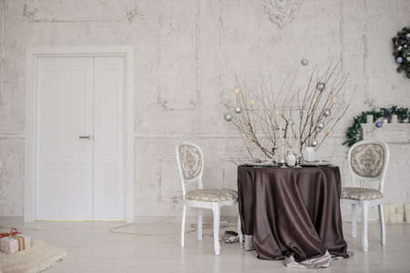 A winter studio background: a table with two chairs near a white fireplace and a doorの写真素材