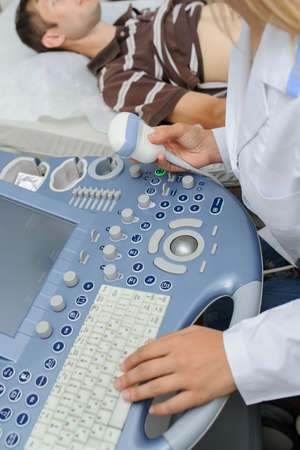 The lady  doctor  examination a man at abdomen with ultrasonography deviceの写真素材
