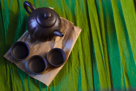 Three cups and a kettle of ceramics on the green background, close viewの写真素材