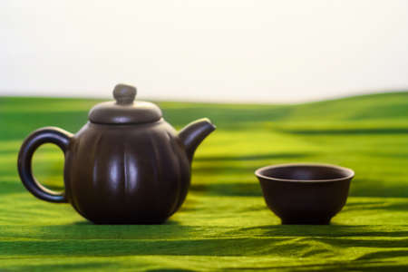 A cup and a kettle of ceramics on the green background, close viewの写真素材