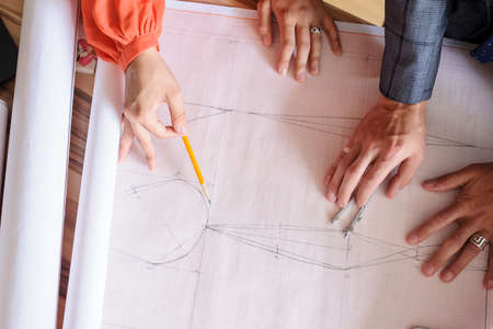 A office desk with architecture project and working handsの写真素材