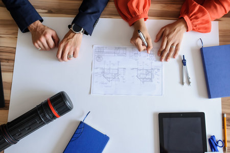 A office desk with architecture project and working hands, top view
