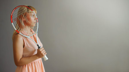 A pretty blonde girl with tennis palette, close view, grey backgroundの写真素材