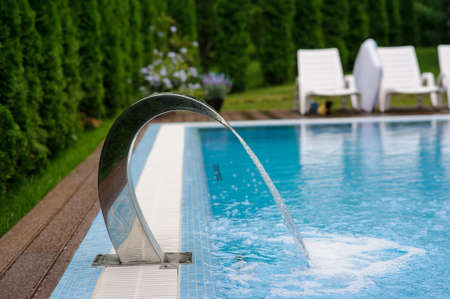 View of a empty swimming pool with blue water outside. Light day and clean background outside in the garden.の写真素材