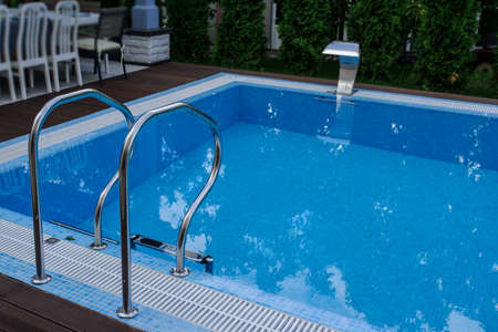 View of a empty swimming pool with blue water outside. Light day and clean background outside in the garden.の写真素材