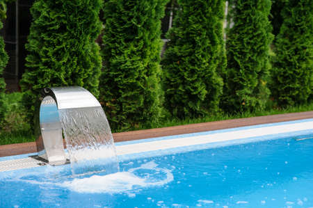 View of a empty swimming pool with blue water outside. Light day and clean background outside in the garden.の写真素材