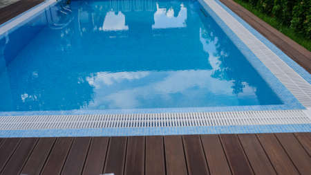 View of a empty swimming pool with blue water outside. Light day and clean background outside in the garden.の写真素材