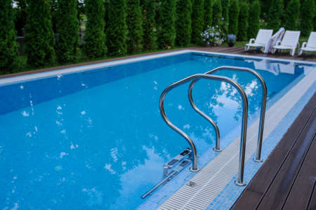 View of a empty swimming pool with blue water outside. Light day and clean background outside in the garden.の写真素材
