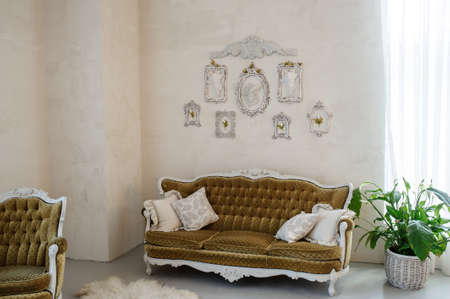 Sofa and chair in the wedding decor studio. One sofa and one chair with flowers and frames on the wall.の写真素材